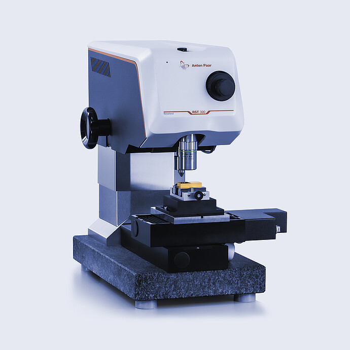Angled view of the Anton Paar Revetest® Scratch Tester RST 100 with the indenter positioned above a sample on the testing base.