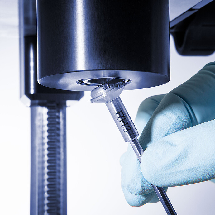 Gloved hand attaching a spindle to the ViscoQC ASTM D2983 viscometer for automated low-temperature lubricant testing.