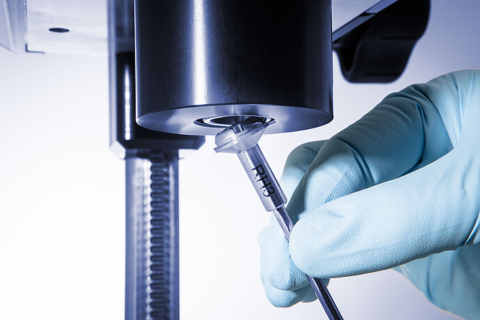 Gloved hand attaching a spindle to the ViscoQC ASTM D2983 viscometer for automated low-temperature lubricant testing.