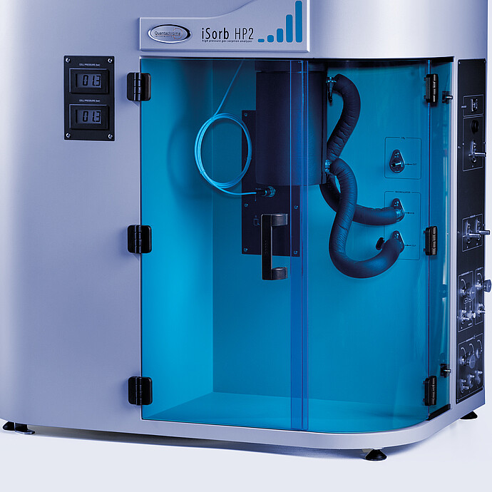 Close-up of the Anton Paar iSorb HP2 high-pressure gas sorption analyzer, showing the thermostatically controlled manifold with tubing and connections inside a transparent blue-front chamber. The control panel on the side highlights the safety features, including automated valve closure and pressure monitoring for high-pressure gas experiments.