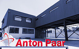 Anton Paar Chile building with dark metal facade and elevated structure, red Anton Paar logo sign in foreground courtyard