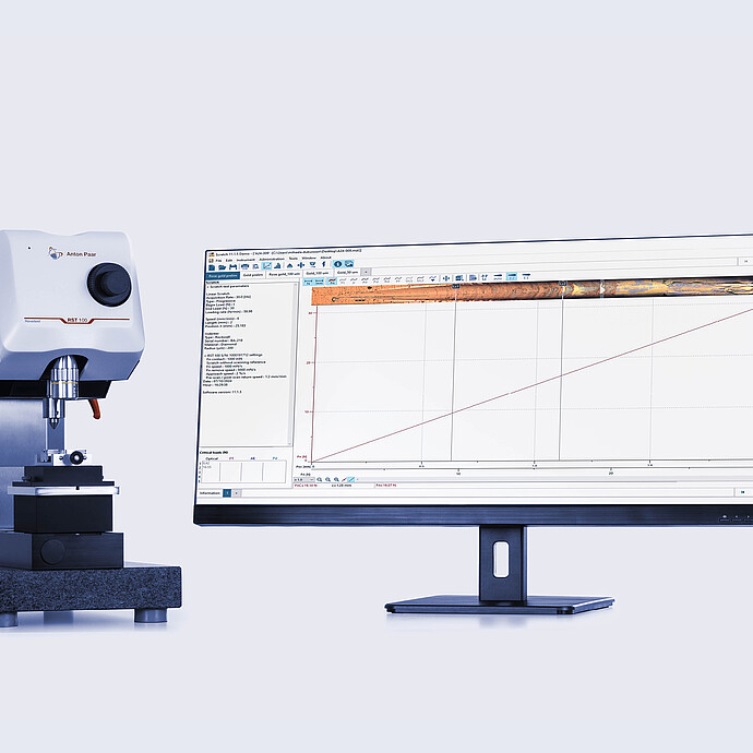Anton Paar Revetest® Scratch Tester RST 100 beside a computer monitor displaying detailed scratch test data and results in a laboratory setup.