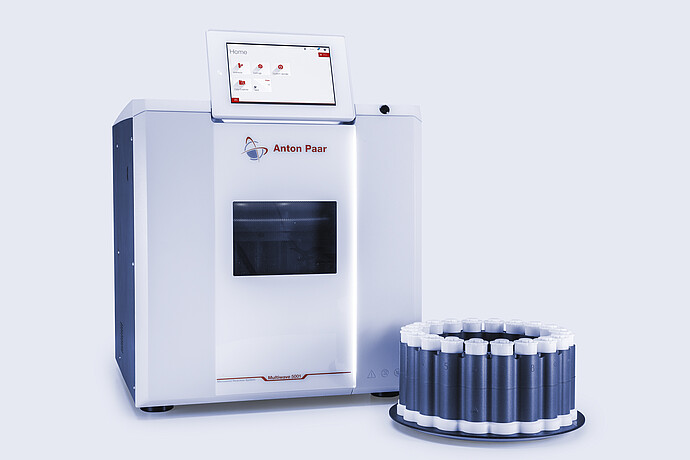 Multiwave 5001 microwave digestion system beside a rack with white-capped microwave digestion vessels.