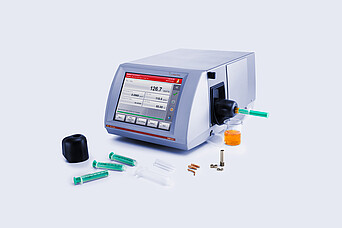 Anton Paar SVM 3001 rotational viscometer with Hot Filling Attachment mounted on the filling port, shown with syringes, filling accessories, and a beaker containing heated high-viscosity sample.
