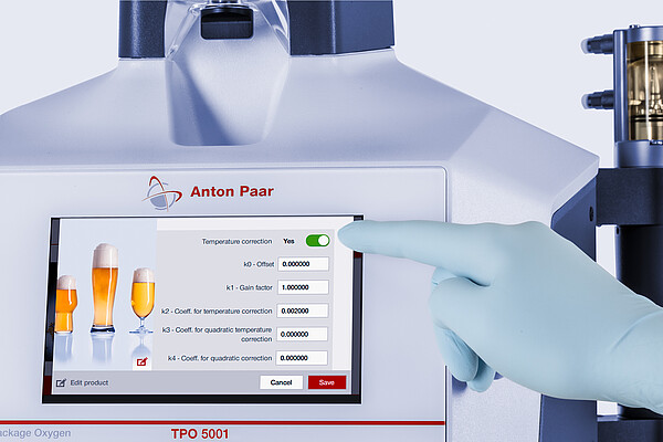 Gloved hand selects temperature correction settings on the Anton Paar TPO 5001 touchscreen interface for total package oxygen measurement.