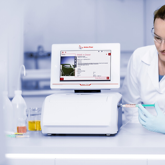 Laboratory technician injects a sample into the Lyza Flow Cell connected to an Anton Paar Lyza 7000 FTIR spectrometer.