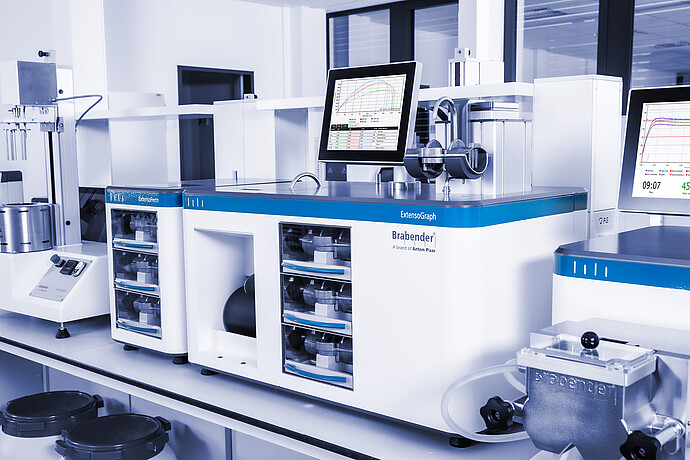Brabender ExtensoGraph with ExtensoForm modules and integrated touchscreen showing measurement curves, laboratory bench setup with adjacent Brabender FarinoGraph