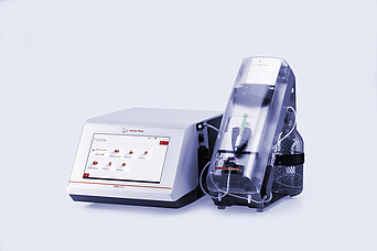 Anton Paar DMA 5002 density meter with touchscreen connected to Xsample 340 sample changer under a clear cover and bottle