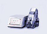 Anton Paar DMA 5002 density meter with touchscreen connected to Xsample 340 sample changer under a clear cover and bottle