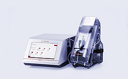 Anton Paar DMA 5002 density meter with touchscreen connected to Xsample 340 sample changer under a clear cover and bottle