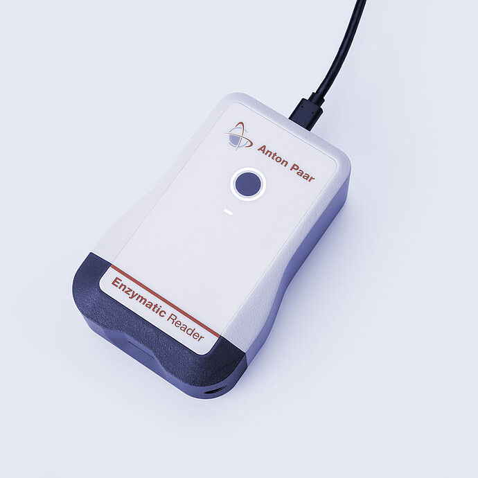 Anton Paar Enzymatic Reader digital ethanol meter with illuminated button and USB cable on light gray background.