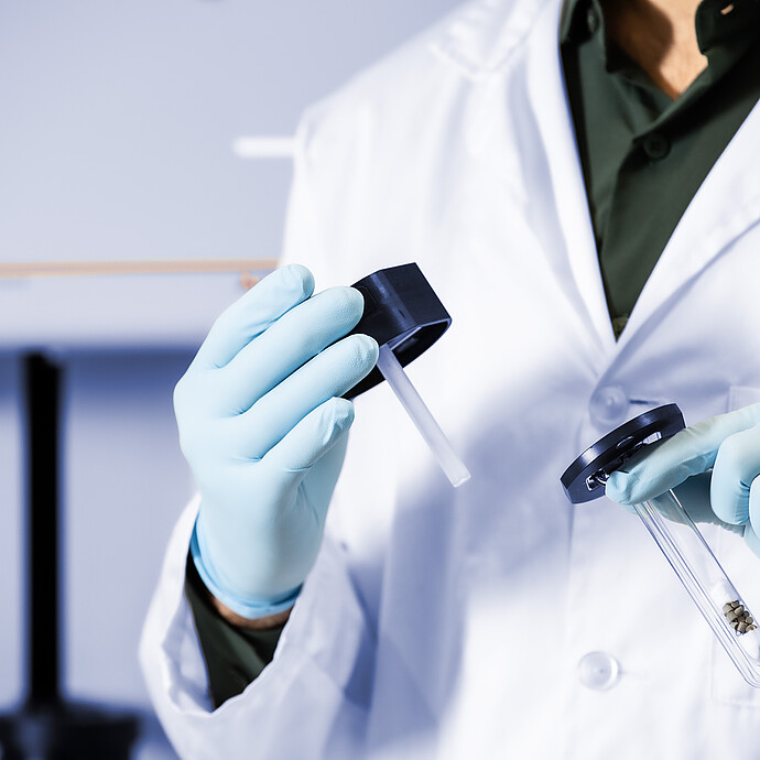 Technician in gloves holding a sample tube and holder for the Anton Paar Autosorb 3300 chemisorption analyzer