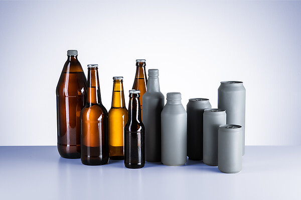Assorted beer packaging formats including brown glass bottles and aluminum cans in different sizes, arranged upright on a light background