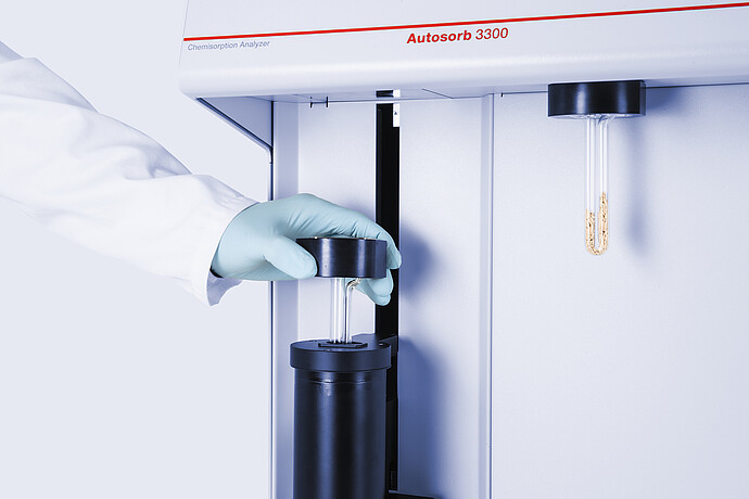 Gloved hand placing a glass sample tube in the Anton Paar Autosorb 3300 chemisorption analyzer