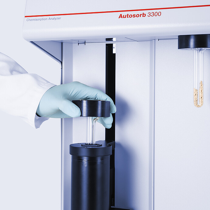 Gloved hand placing a glass sample tube in the Anton Paar Autosorb 3300 chemisorption analyzer