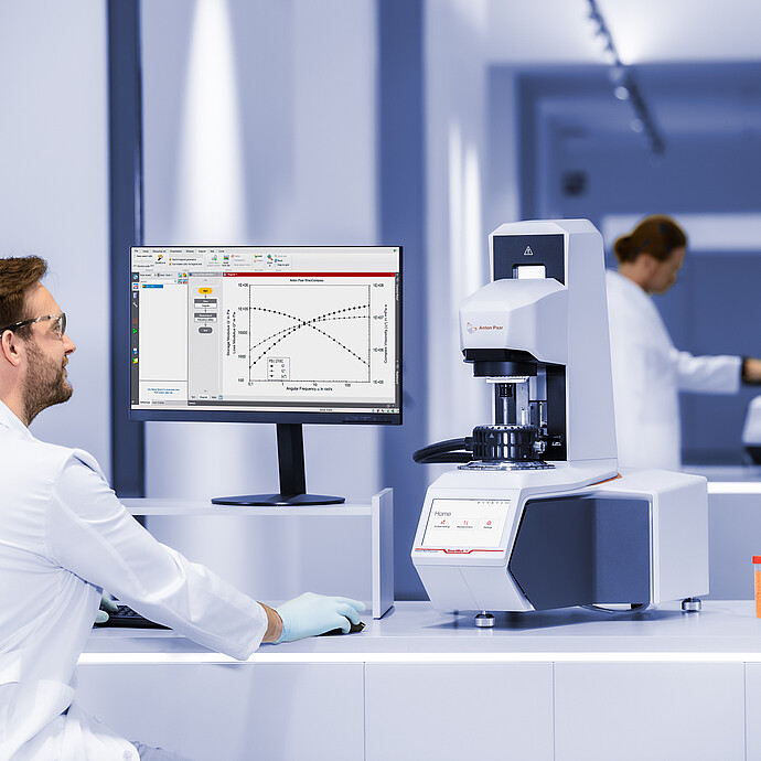 Lab technician reviews results beside an Anton Paar SmartMelt 73 polymer melt rheometer in a laboratory.