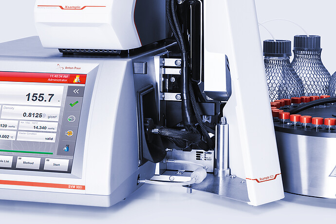 Close-up of Anton Paar SVM 3001 with Xsample Heating Controller and Xsample 631 sample changer, tubing, red-capped vial carousel, and bottles