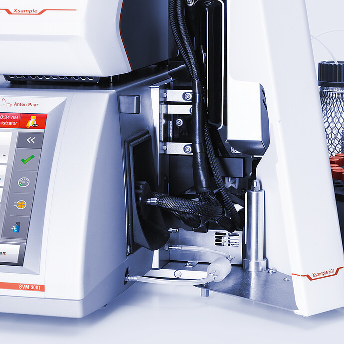 Close-up of Anton Paar SVM 3001 with Xsample Heating Controller and Xsample 631 sample changer, tubing, red-capped vial carousel, and bottles