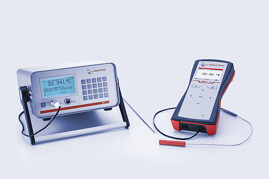 Anton Paar MKT 50 benchtop thermometer and MKT 10 handheld thermometer with connected temperature probes on light background.