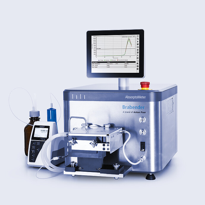 Brabender AbsorptoMeter with closed measuring chamber and integrated display showing torque curve, connected via tubing to dosing unit and reagent bottle on lab bench