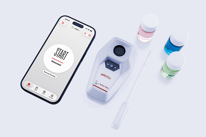 Anton Paar pH2Go digital pH meter beside a smartphone showing the pH2Go app start screen, with buffer solution bottles and a pipette arranged on a light surface.