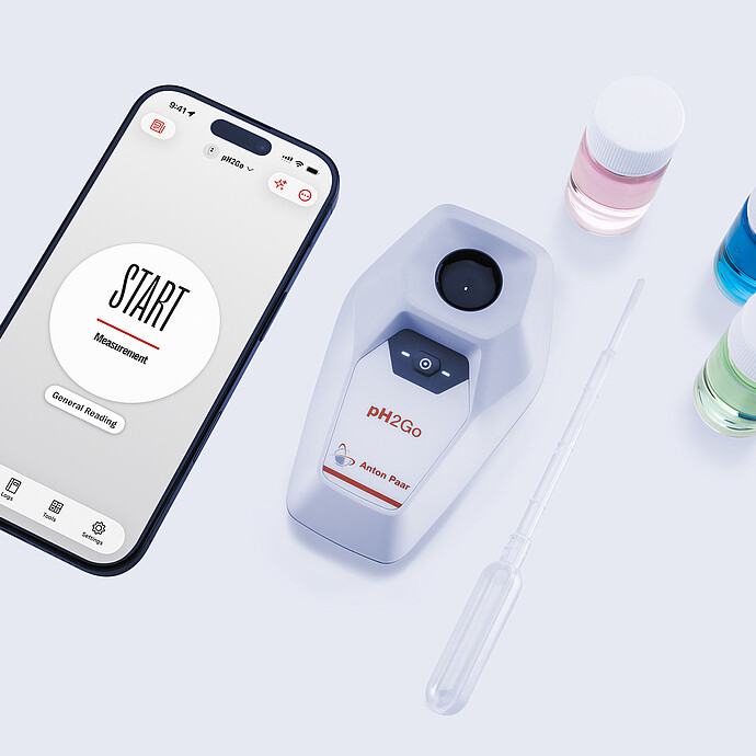 Anton Paar pH2Go digital pH meter beside a smartphone showing the pH2Go app start screen, with buffer solution bottles and a pipette arranged on a light surface.