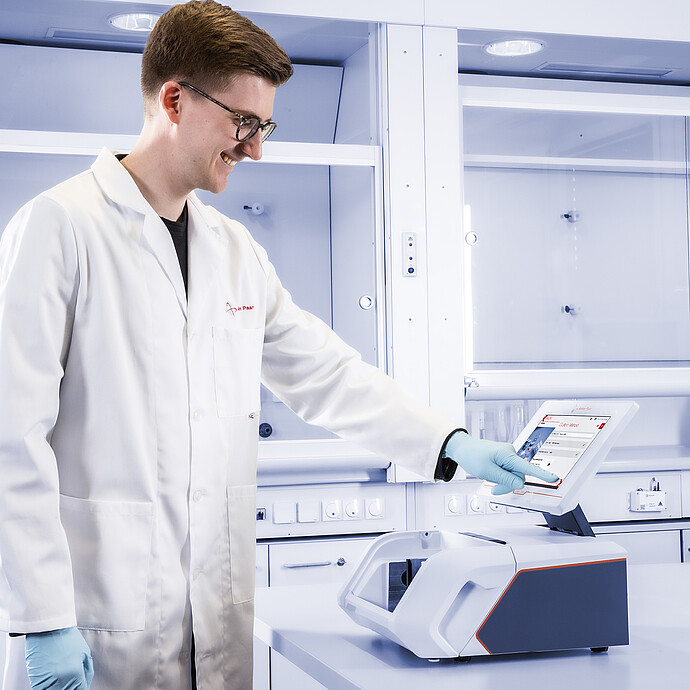 Laboratory technician operates the Anton Paar Lyza 7000 FTIR spectrometer via its integrated touchscreen on a laboratory bench.