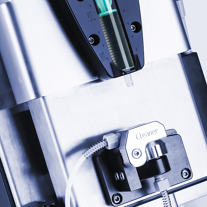 Close-up of Anton Paar Xsample 340 sample changer with 1 mL syringe above a cleaner port and connected tubing