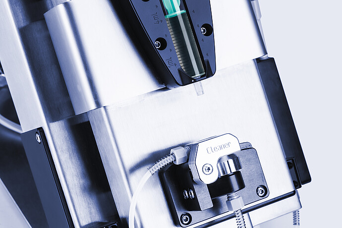 Close-up of Anton Paar Xsample 340 sample changer with 1 mL syringe above a cleaner port and connected tubing