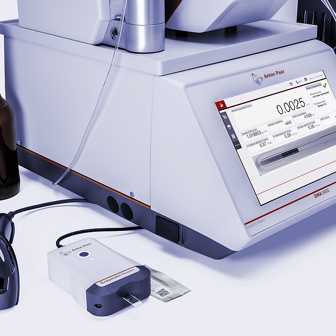 Anton Paar DMA 5002 with Enzymatic Reader digital ethanol meter, barcode scanner, beer bottle, and beverage can for packaged beer analysis.