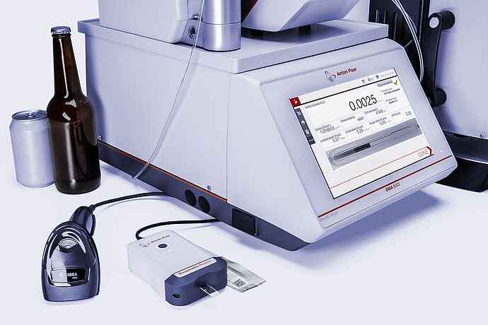Anton Paar DMA 5002 with Enzymatic Reader digital ethanol meter, barcode scanner, beer bottle, and beverage can for packaged beer analysis.
