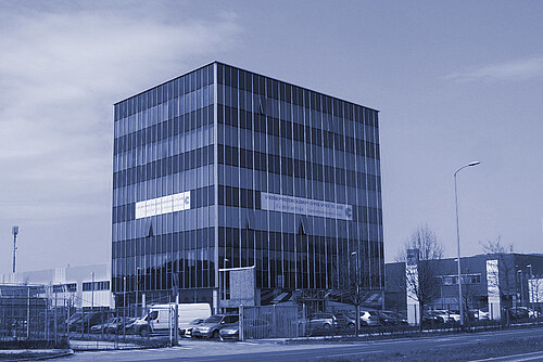 Anton Paar Croatia office building, a modern multi-story structure with a glass facade, located in an industrial area with parked cars and adjacent road access.