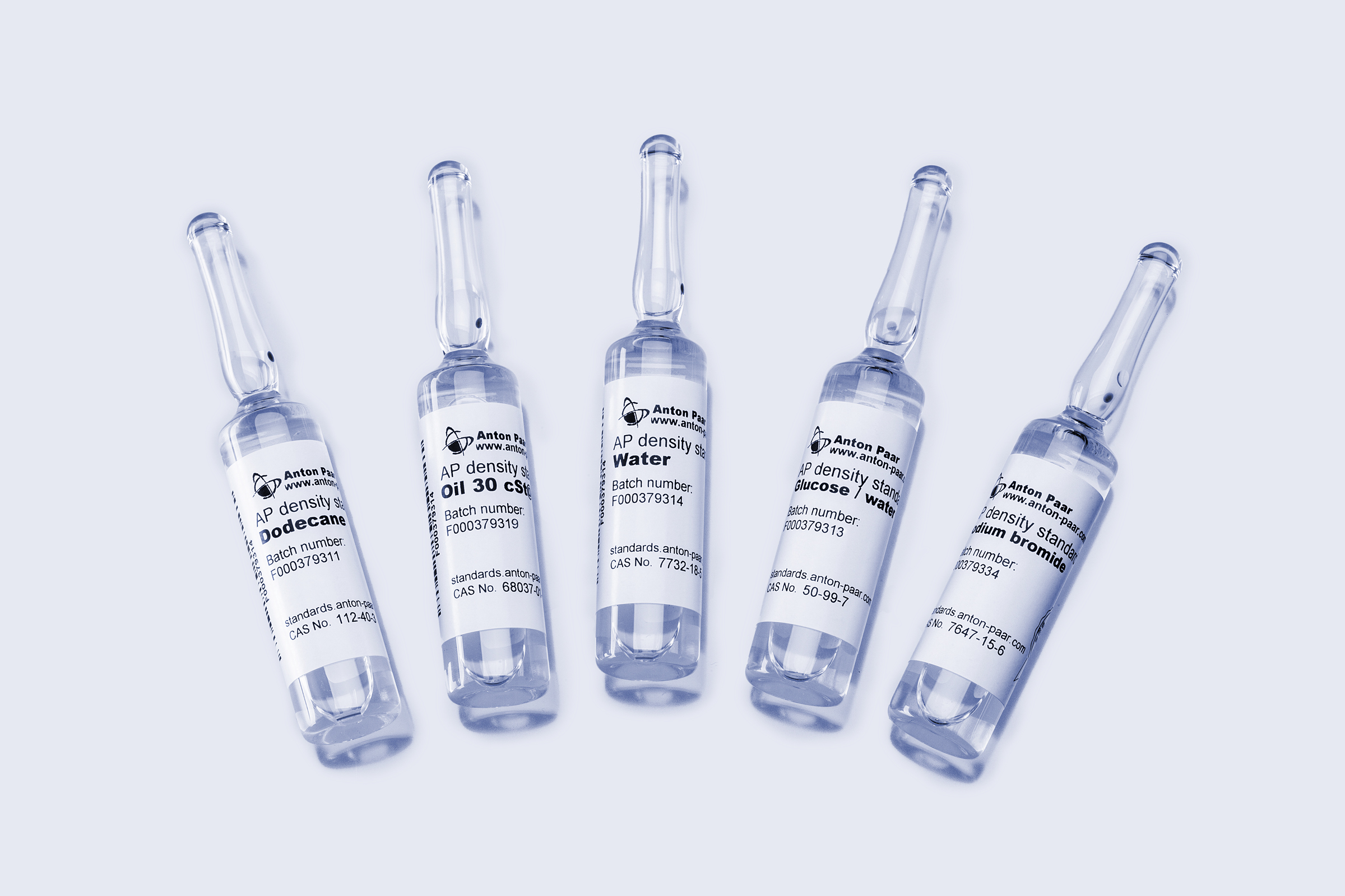 Five Anton Paar AP density standards ampoules labeled dodecane, Oil 30, Water, glucose/water, and sodium bromide on light background.